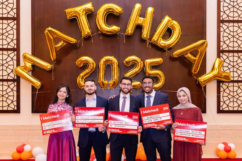 five students holding signs during a celebration
