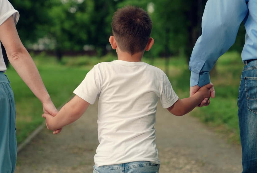 photo of child between parents, holding hands