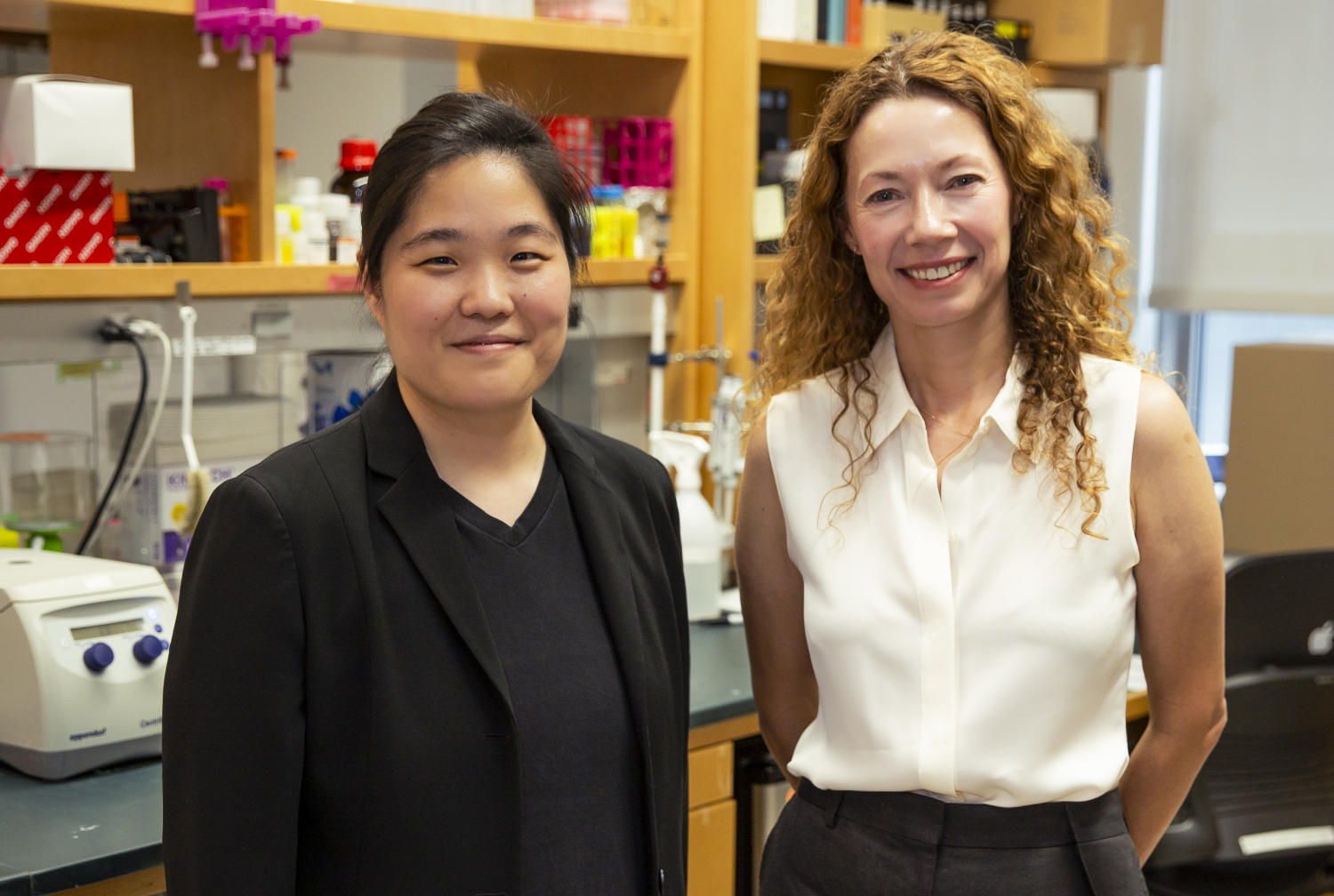 Two women pose for a photo in a lab