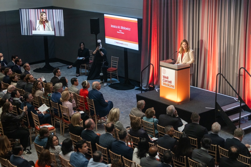 a woman at a podium speaking to a crowd of people