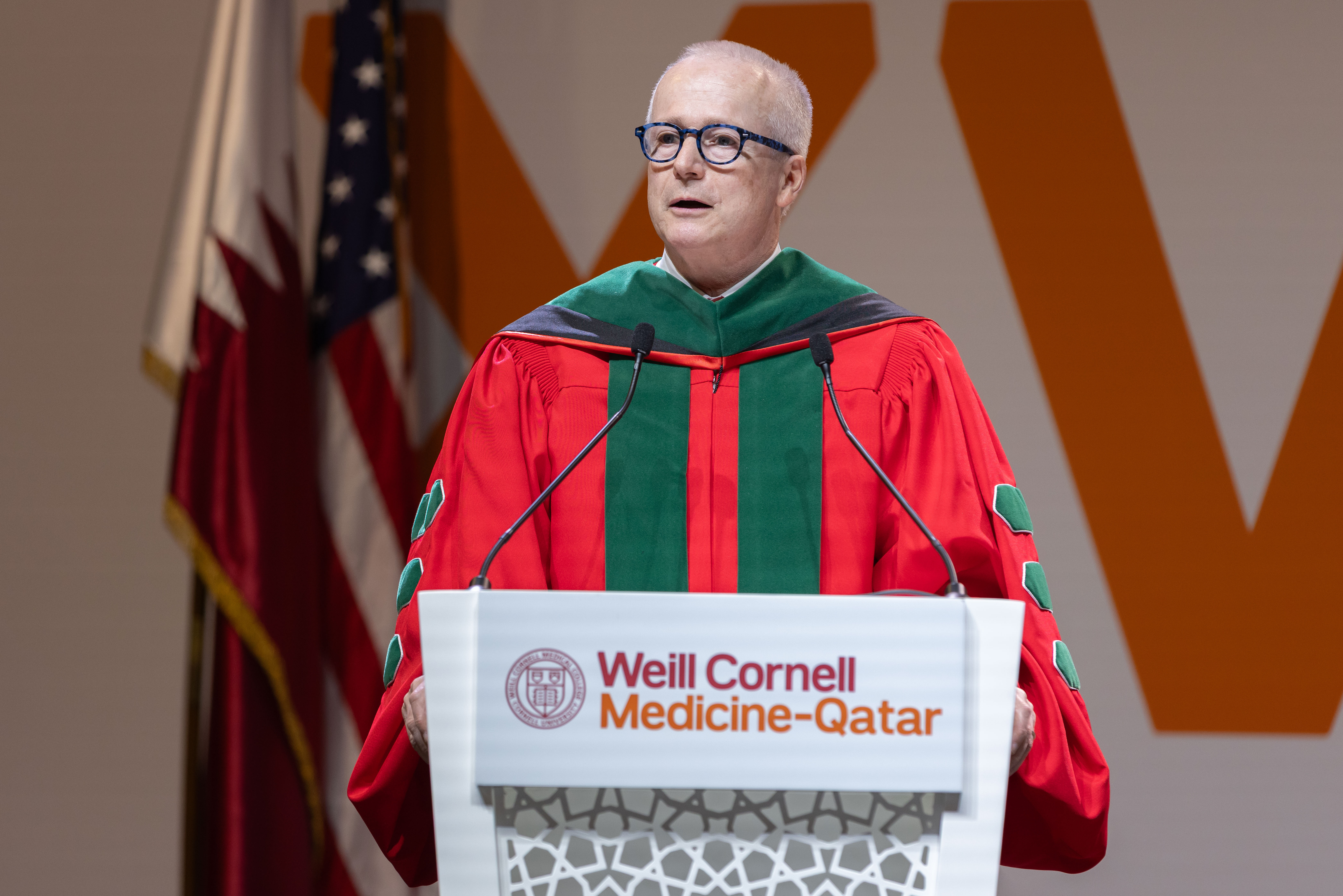 A man wearing graduation regalia standing at a podium