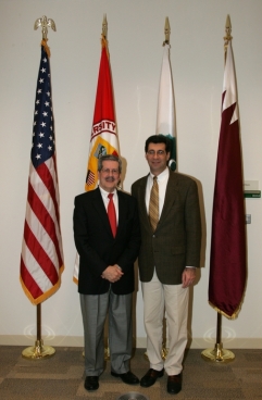 Two men standing behind four flags