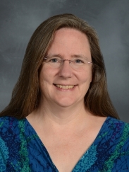 a woman in glasses smiling for a portrait