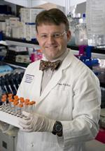 man in white coat holding tray of test tubes