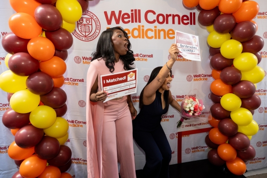 A woman wearing a pink dress behind a balloon arch