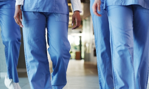 photo of the legs of people wearing scrubs walking in a hallway