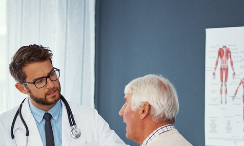 doctor talking to an older man sitting on a bed