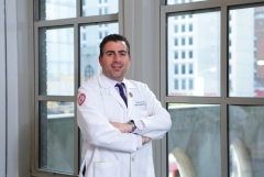 portrait of a man wearing a white coat in front of a window