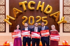 five students holding signs during a celebration