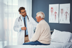 doctor talking to an older man sitting on a bed