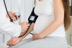 photo of doctor taking pregnant woman's blood pressure