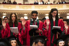 Students in graduation regalia reciting an oath
